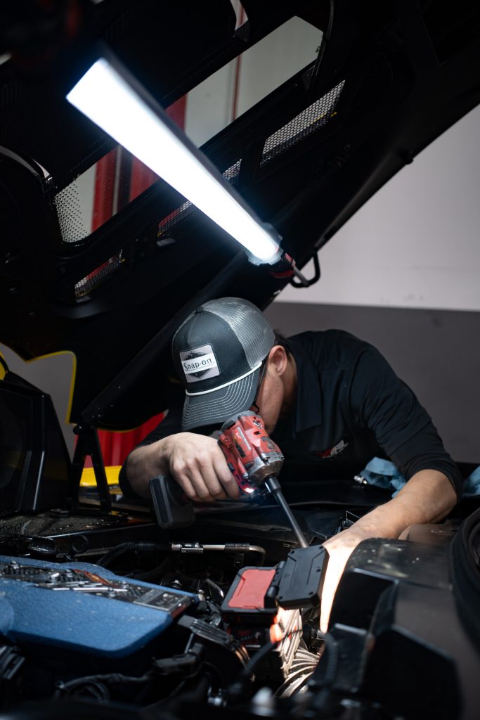 Vengeance Racing technician installing headers in the shop